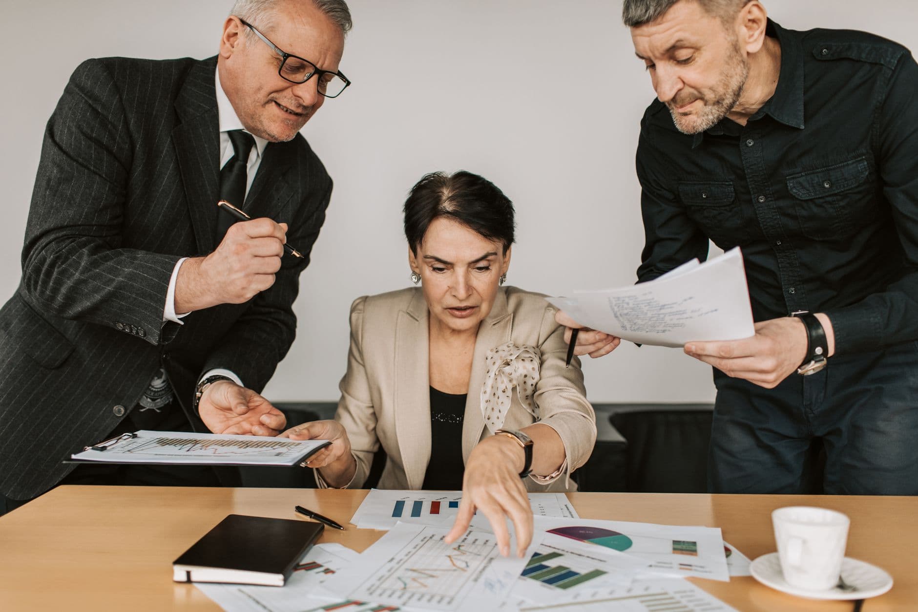 Three finance professionals reviewing charts and reports together at a desk